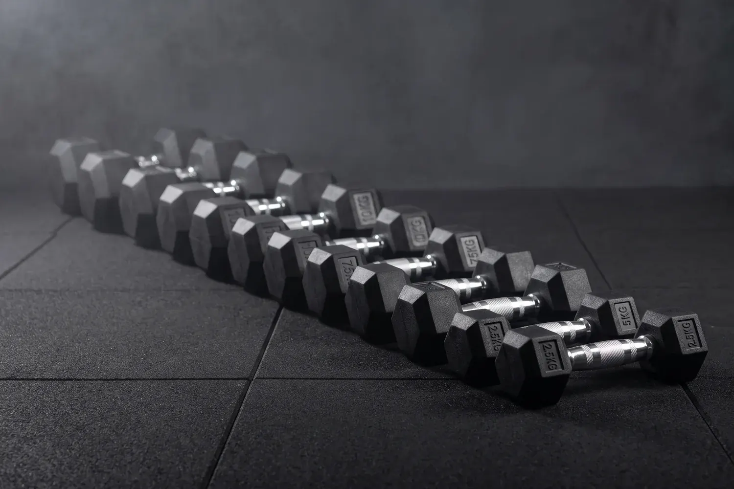 Haltères hexagonaux Uni Strength alignés au sol